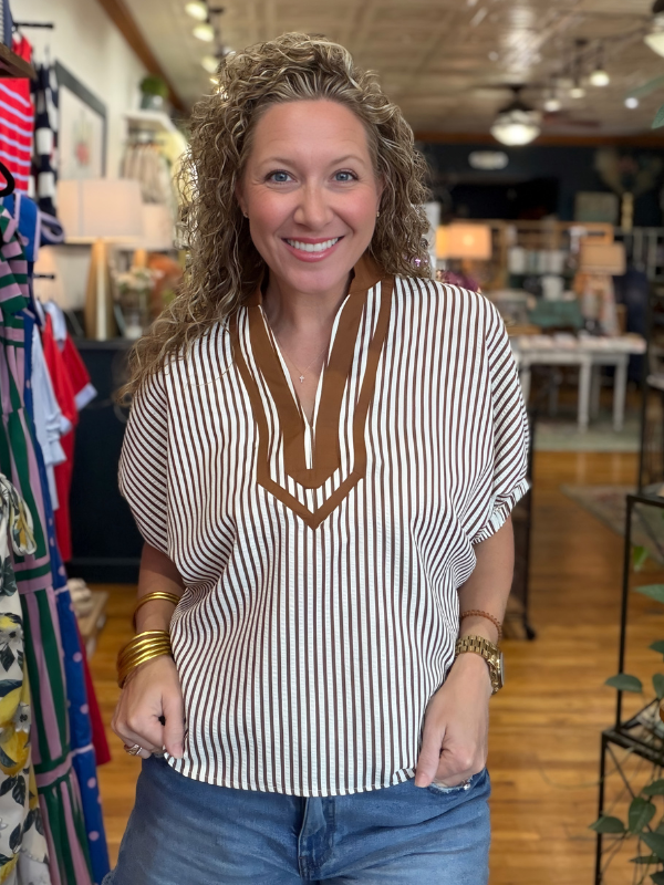 Woman wearing a striped shirt with a V-neck design in a store setting