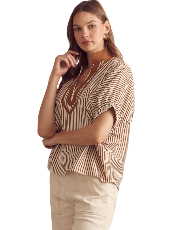 Woman wearing a patterned top and beige pants on a white background
