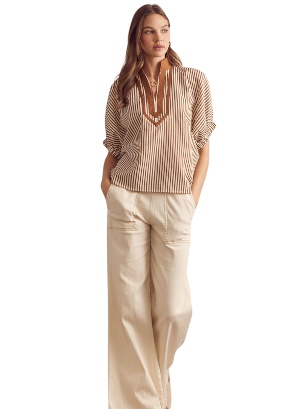 Woman wearing a striped blouse and beige pants on a white background