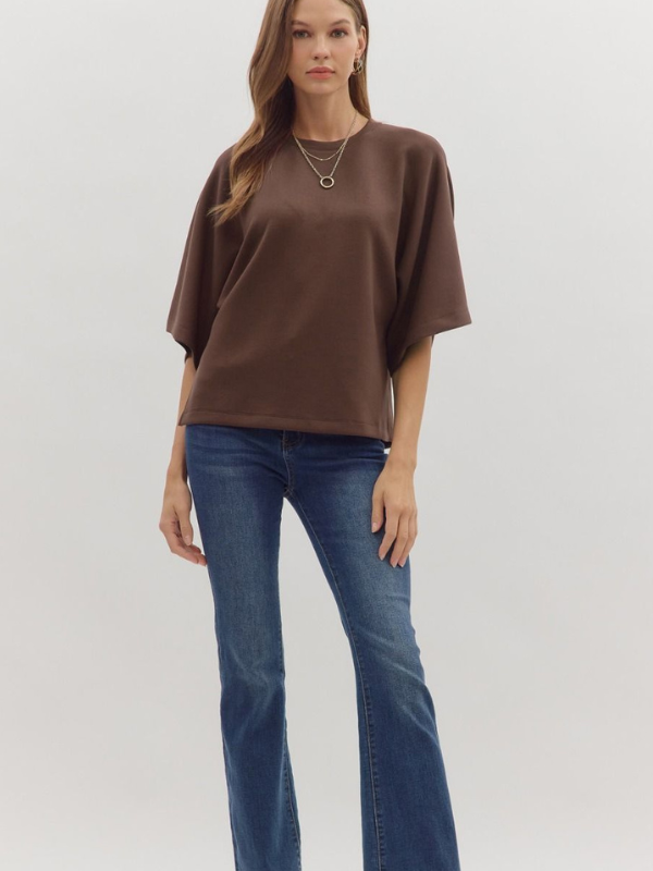 Woman wearing a brown oversized shirt and blue jeans on a white background
