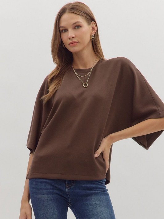 Woman wearing a brown poncho over a plain background
