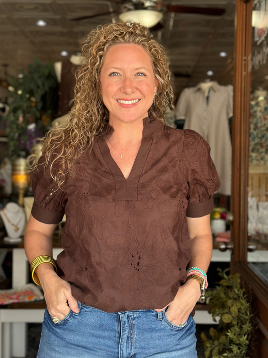 Woman wearing a brown blouse and blue jeans in an indoor setting
