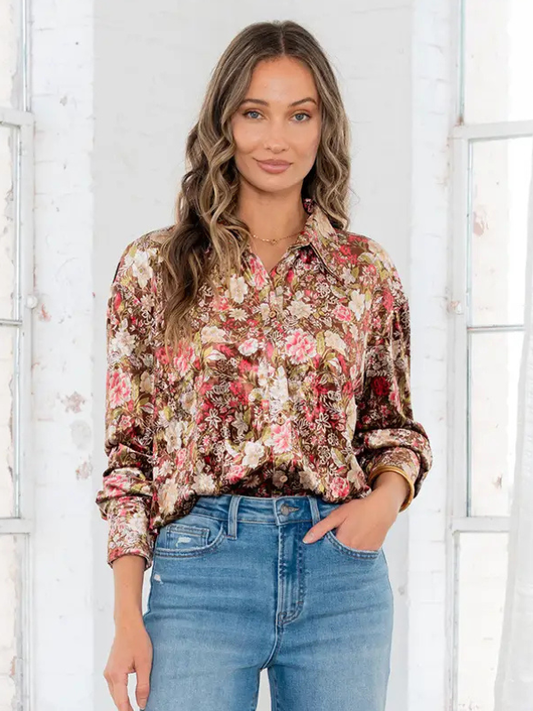 Woman wearing a floral blouse and jeans against a white background