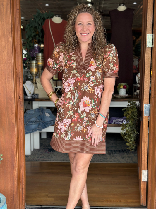 Woman wearing a brown floral dress standing in a store.