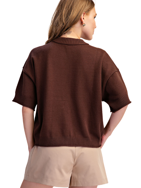 A woman shown from the back wearing a brown short-sleeve knit top and beige shorts against a plain white background.