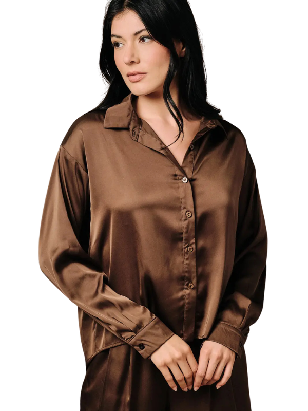 A woman wearing a brown satin button-up shirt and matching satin pajama pants, photographed against a plain white background.