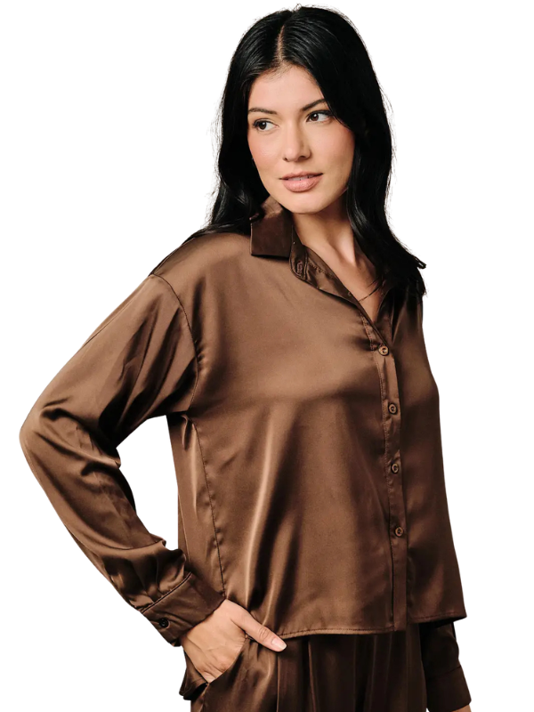 A woman modeling a brown satin long-sleeve button-up shirt against a plain white background.