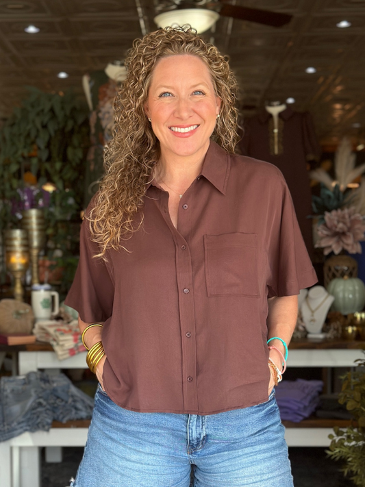 Woman wearing a brown shirt and blue jeans standing in a store setting.