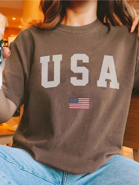Person wearing a brown t-shirt with 'USA' and an American flag design.