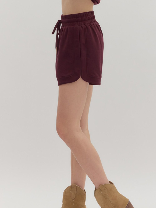 Maroon shorts worn by a person on a plain background