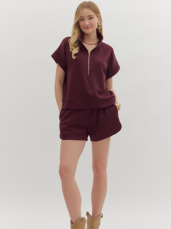 Woman wearing a burgundy outfit with a plain background