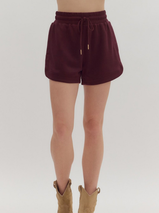 Maroon shorts worn by a person on a plain background
