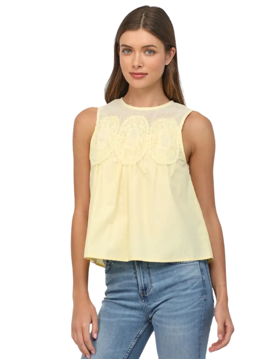 Woman wearing a light yellow sleeveless top and blue jeans on a white background