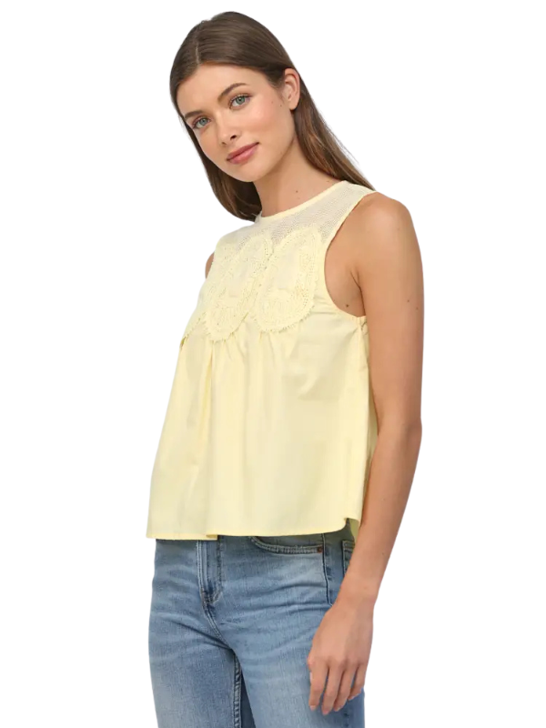 Woman wearing a light yellow sleeveless top and blue jeans on a white background