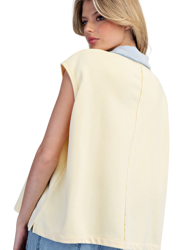 Woman wearing a light yellow sleeveless top with a white background