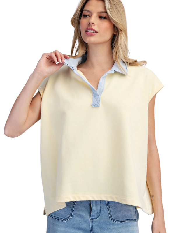 Woman wearing a light yellow sleeveless top with a blue collar on a white background