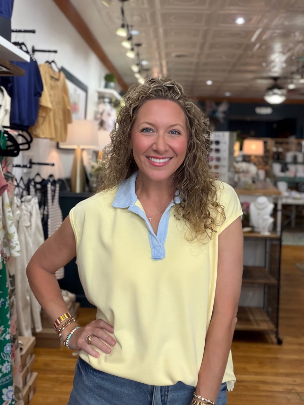 Woman in a yellow top with blue collar standing in a store