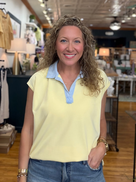 Woman wearing a yellow sleeveless top with a blue collar in a store setting
