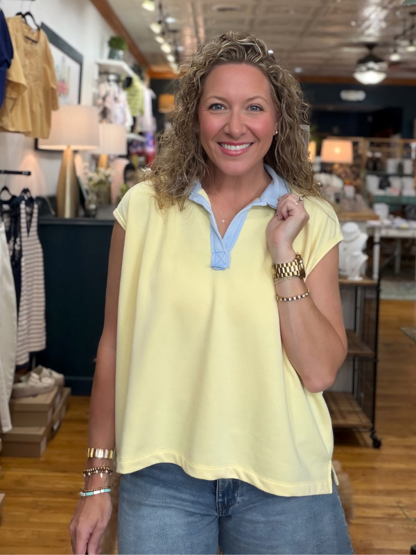 Woman wearing a yellow top with a blue collar in a store setting