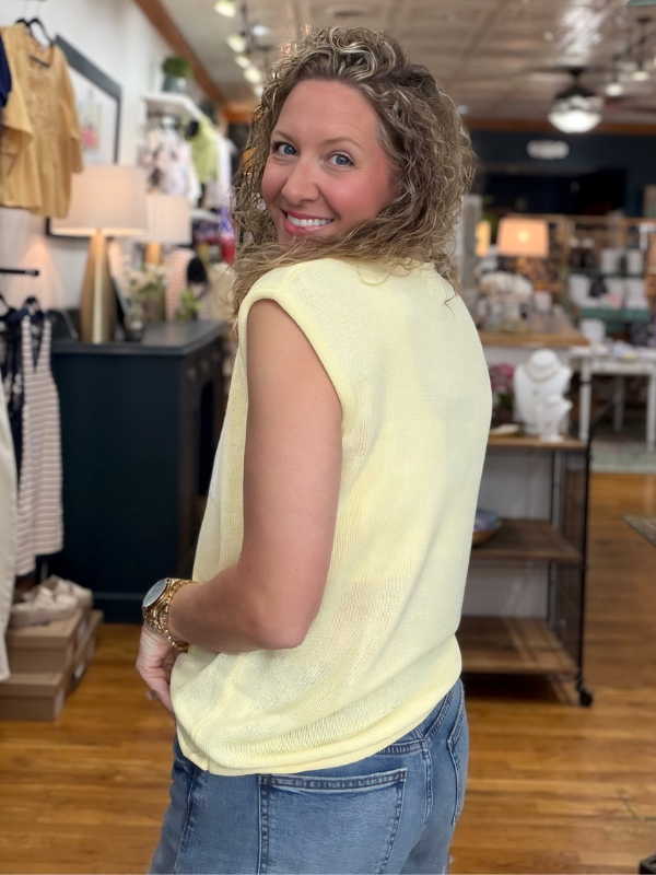 Woman wearing a yellow sleeveless top in a store setting