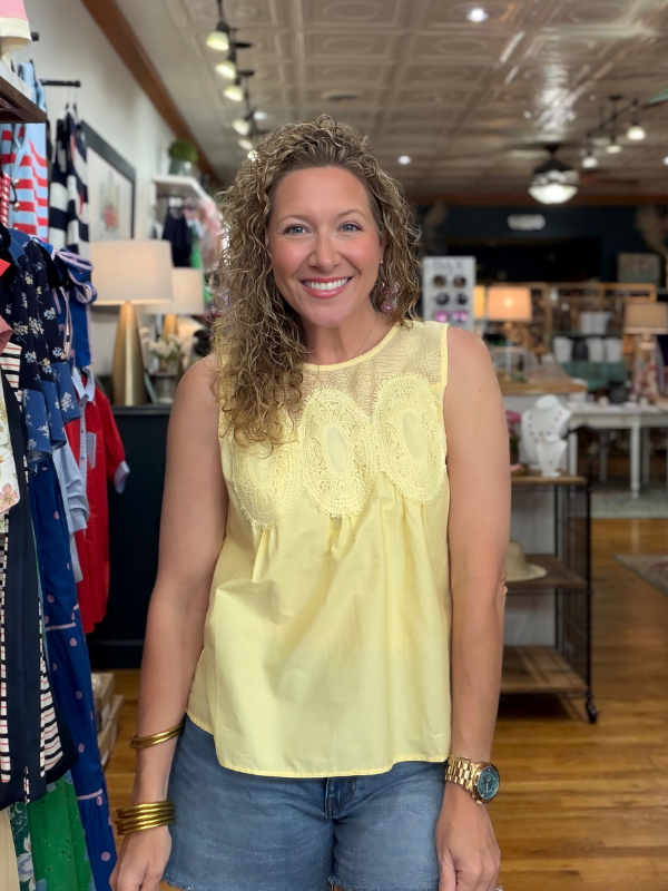 Woman wearing a yellow sleeveless top in a store setting