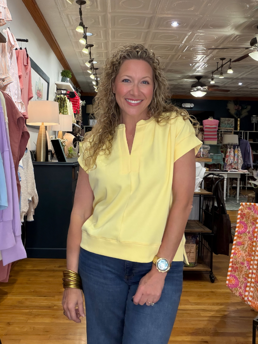 Woman wearing a yellow top and blue jeans in a store setting
