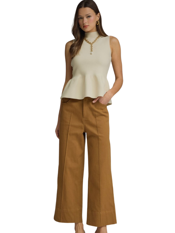 Woman wearing a beige sleeveless top and brown wide-leg pants on a white background