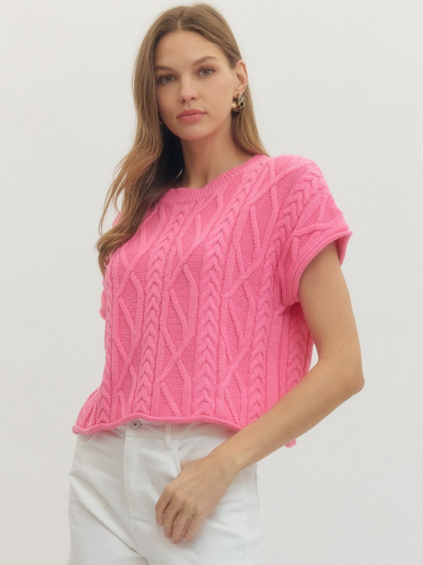 Woman wearing a pink knitted top against a white background