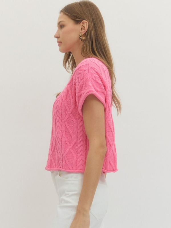 Woman wearing a pink knitted top against a white background