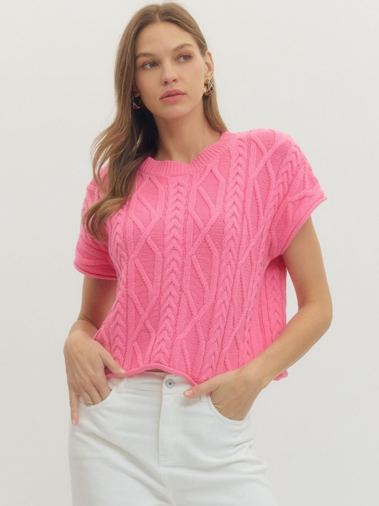 Woman wearing a pink knitted top against a white background