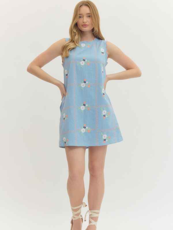 Woman wearing a light blue dress with floral pattern on a white background