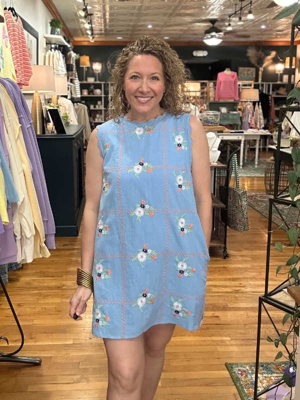 Woman wearing a blue dress with floral pattern in a store setting