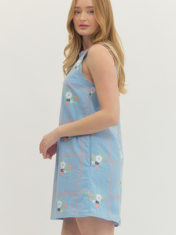 Woman wearing a light blue dress with floral patterns on a white background