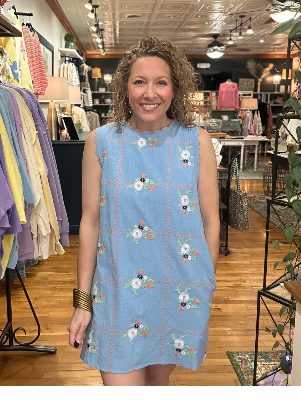 Woman wearing a blue dress with floral patterns in a store setting