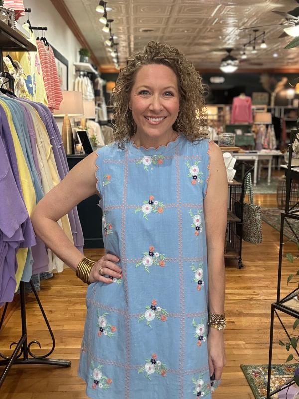Woman wearing a blue floral dress in a clothing store.