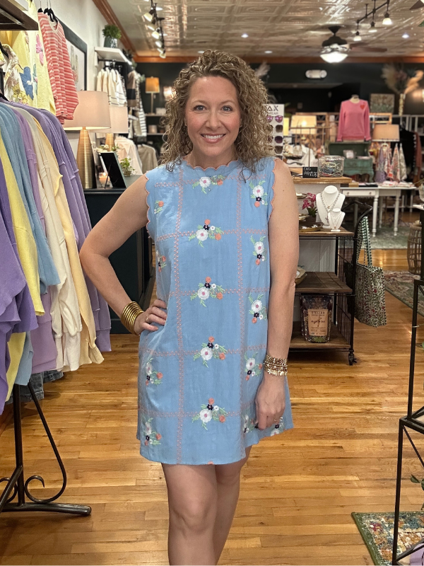 Woman wearing a blue dress with floral patterns in a store setting