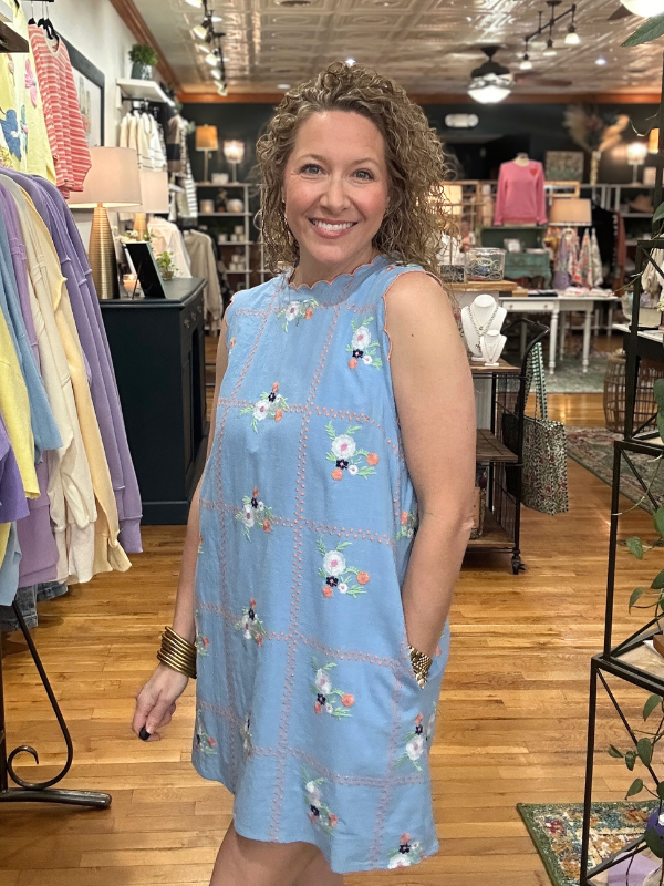 Woman wearing a blue dress with floral patterns in a store setting
