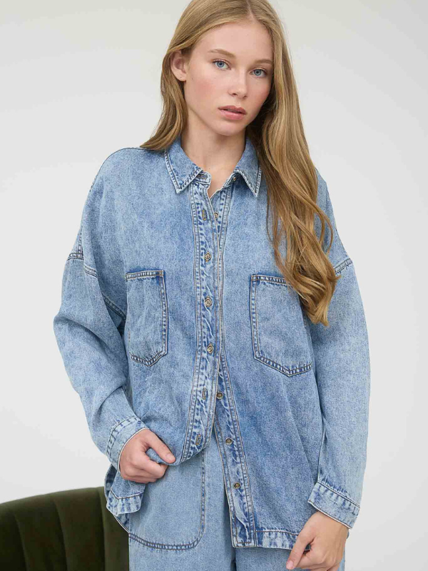 Woman wearing a light blue denim shirt against a white background