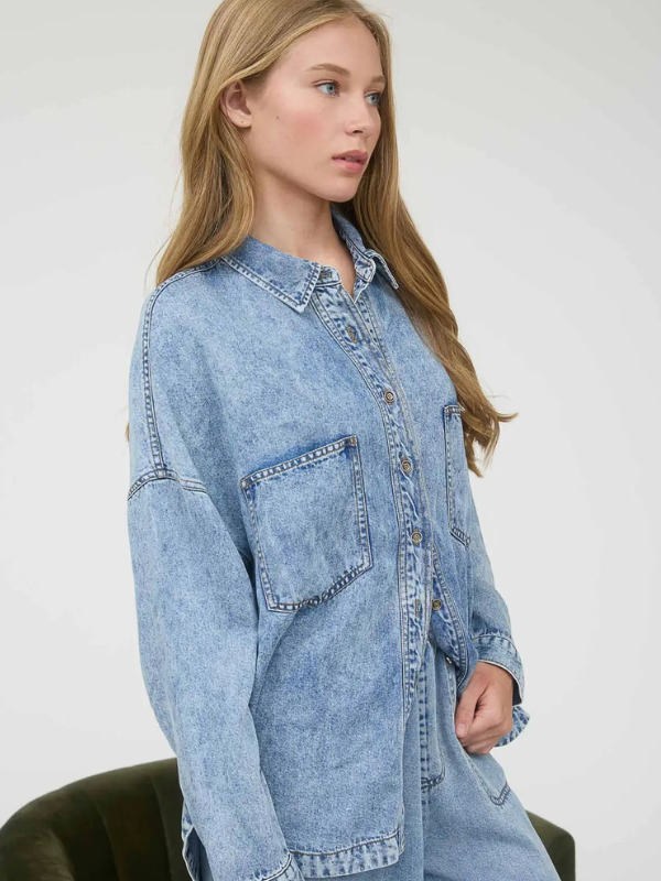 Woman wearing a light blue denim shirt against a white background