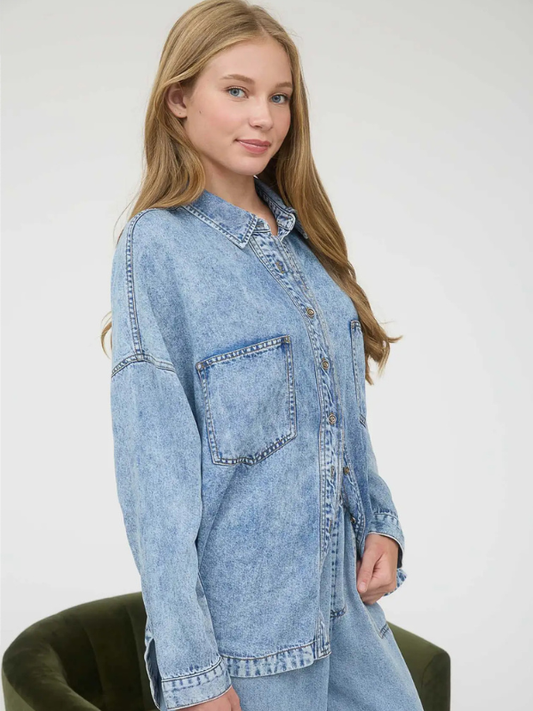 Woman wearing a light blue denim shirt against a white background