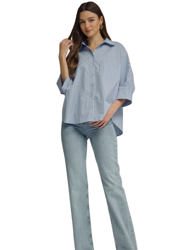 A woman modeling a light blue and white vertically striped button-down shirt with three-quarter sleeves, paired with light-wash blue jeans, against a plain white background.