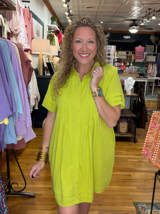 Woman wearing a bright green dress in a clothing store.