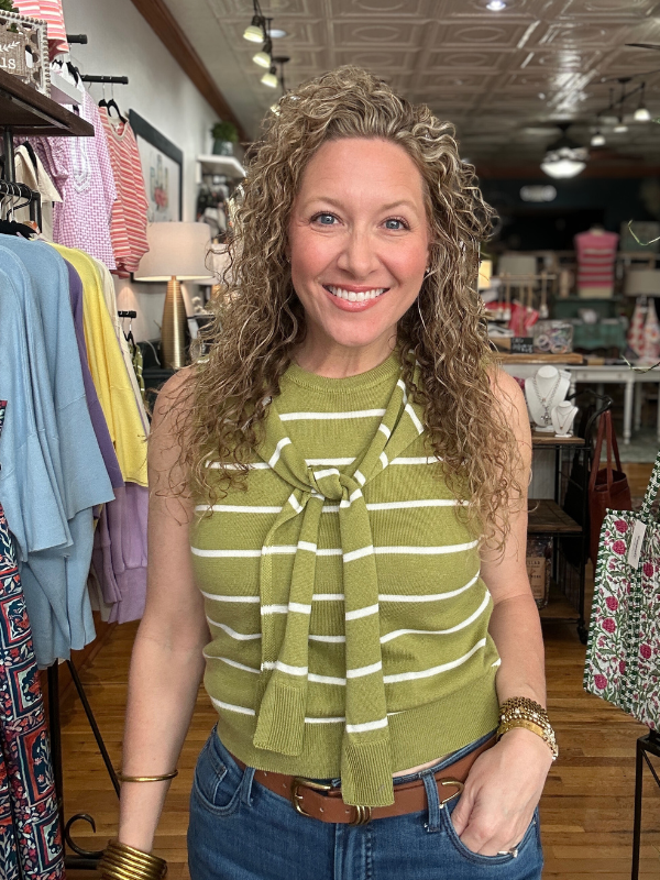 Woman wearing a green striped top with a bow in a clothing store.