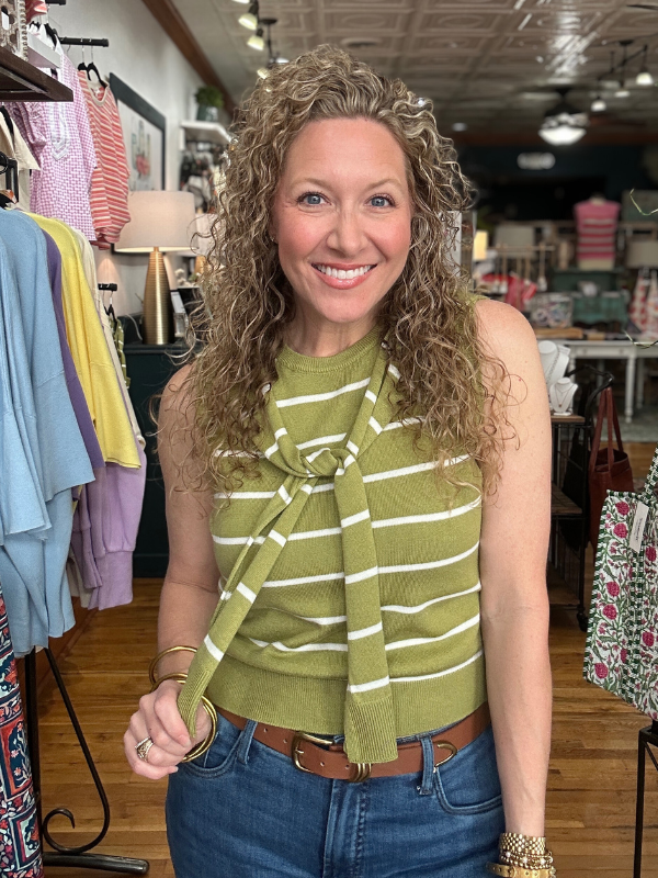 Woman wearing a green striped top and blue jeans in a clothing store.