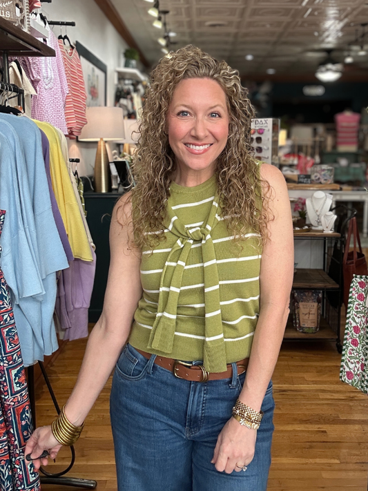 Woman in a green striped top and blue jeans standing in a clothing store.