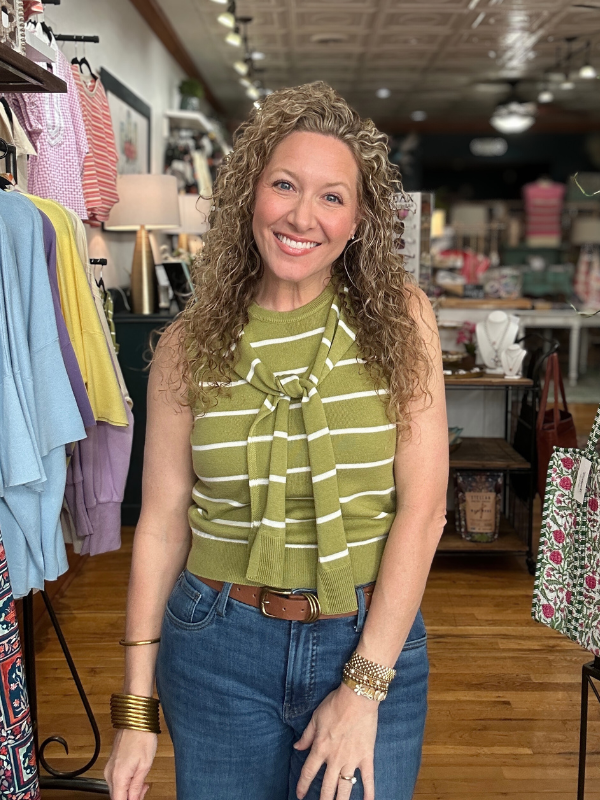 Woman wearing a green striped top and blue jeans in a clothing store.