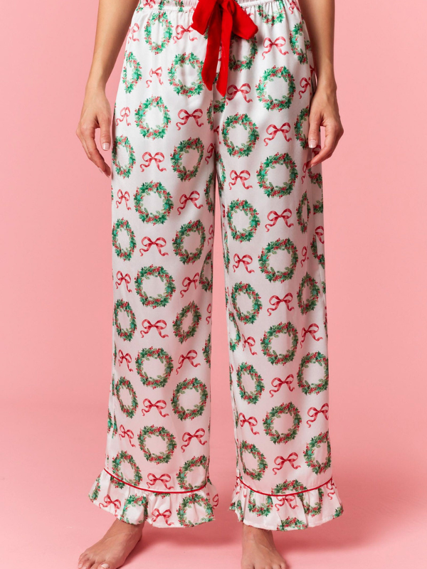 Pajama pants with Christmas wreath and bow pattern on a pink background