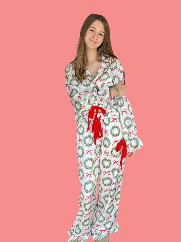 Woman wearing a festive pajama set with red gloves on a pink background
