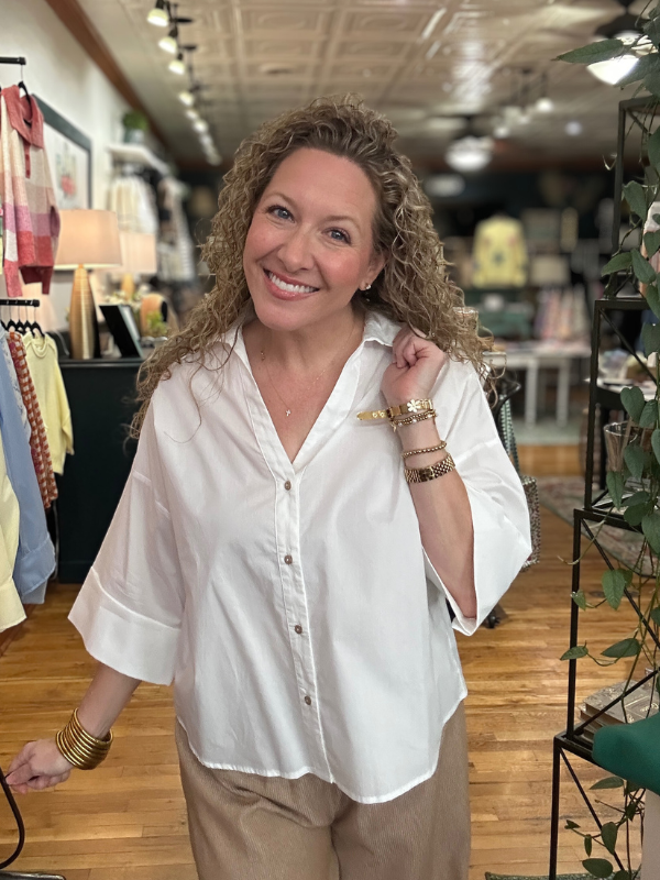 Woman wearing a white blouse and beige pants in a store setting