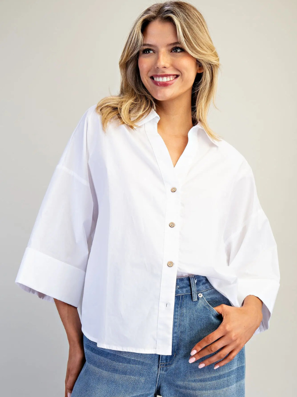 Woman wearing a white blouse and blue jeans against a plain background